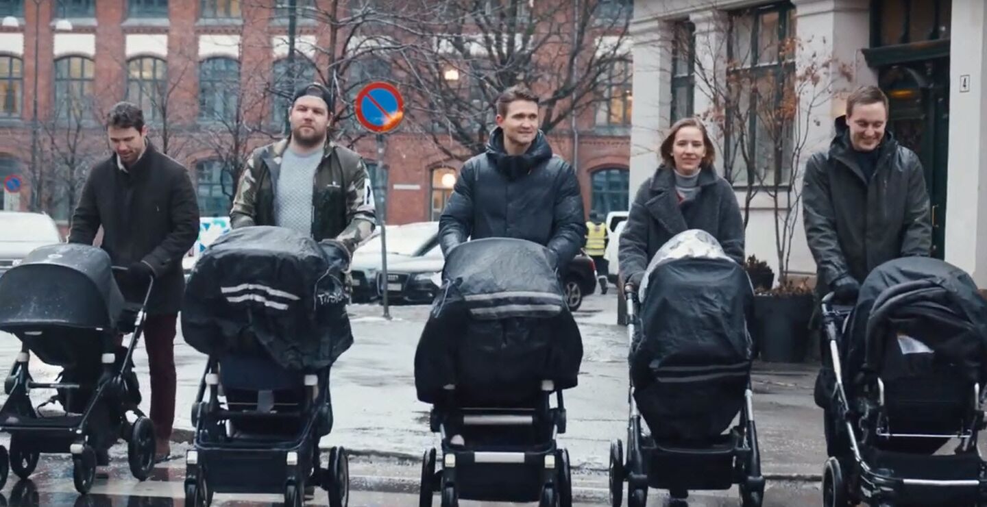 One woman and four men walking with a stroller