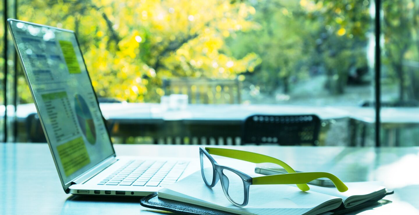 PC, notebook, glasses on a table outside